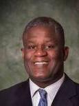 Headshot of Calvin Gantt smiling wearing a suit with tie.