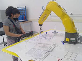 High school student operating FANUC robot in Forward Center summer robotics program